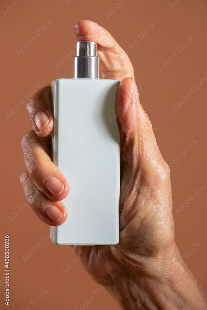 Hand holding a white refillable spray bottle