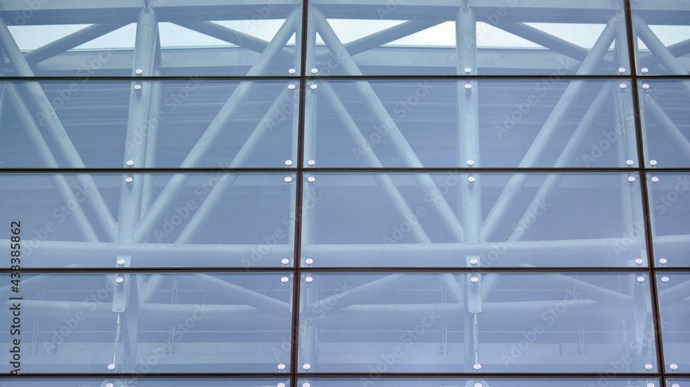 Abstract closeup of the glass-clad facade of a modern building covered in reflective plate glass. Ar