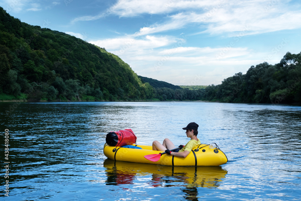 Tourist on yellow packraft rubber boat with red padle