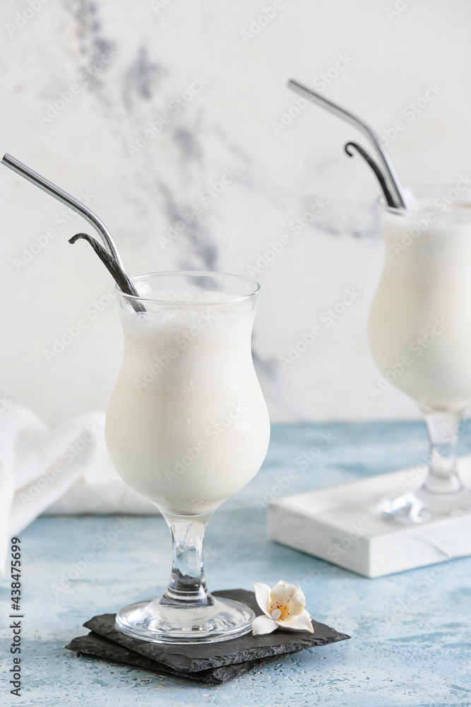 Glasses with tasty vanilla milkshake on color background