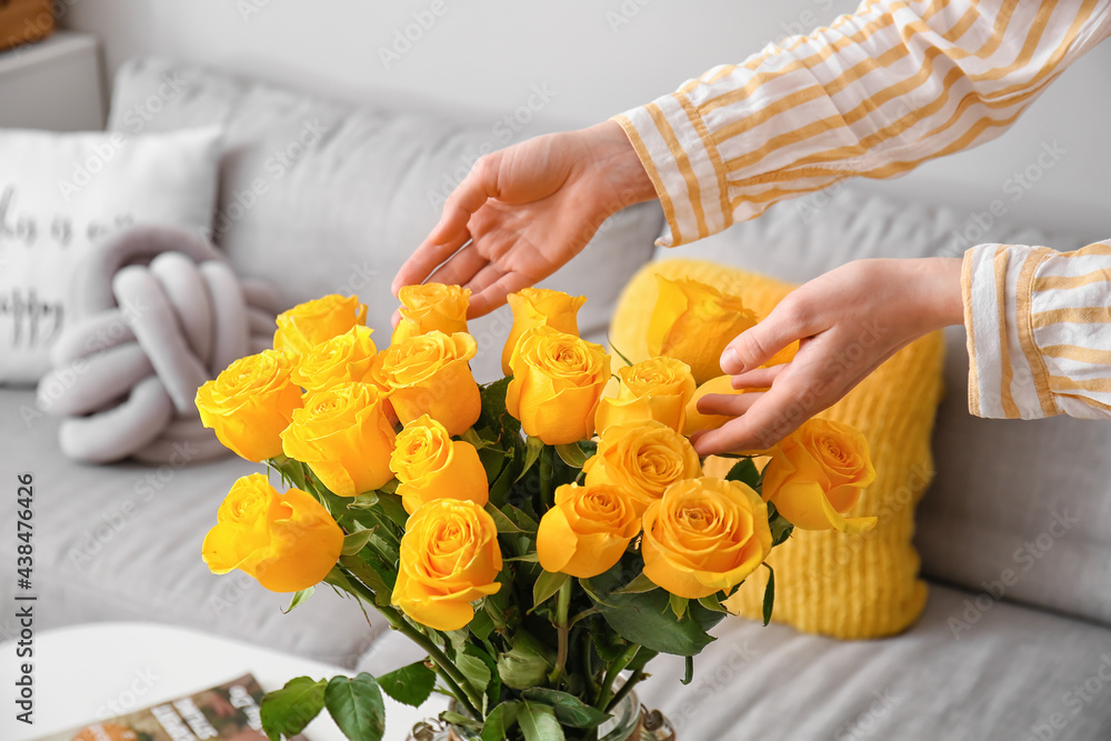 Woman with vase and yellow roses at home