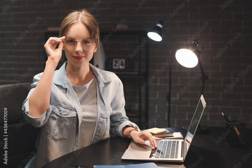 Beautiful woman using laptop at home late in evening