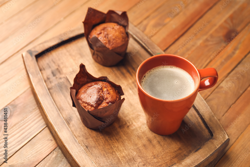 Cup of freshly brewed coffee and muffins on wooden table