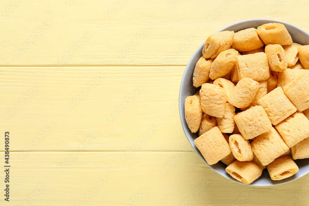 Bowl with tasty corn pillows on color wooden background, closeup