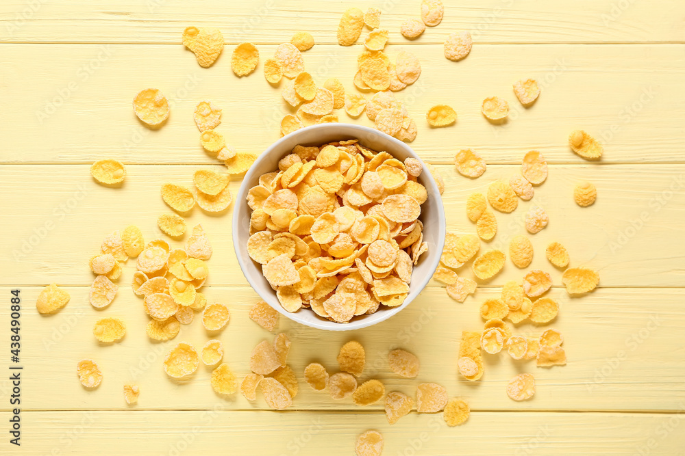 Bowl with tasty corn flakes on color wooden background