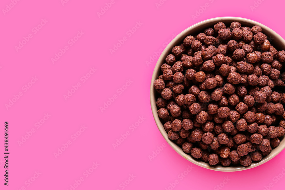 Bowl with chocolate corn balls on color background