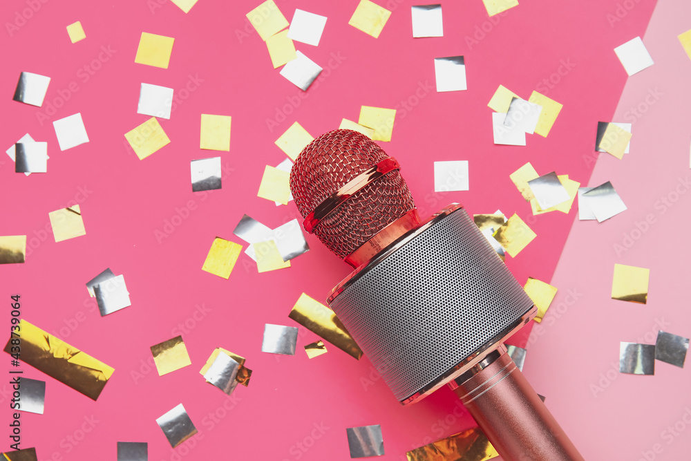 Modern microphone and confetti on color background, closeup