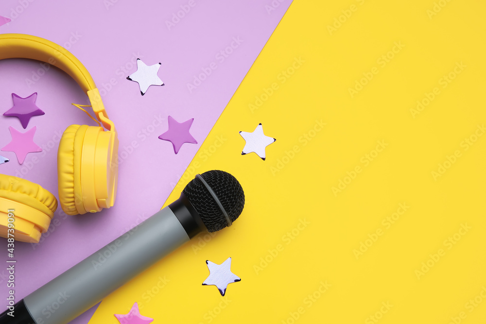 Modern microphone with headphones and confetti on color background