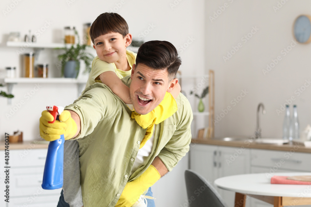 Father and son having fun while cleaning kitchen