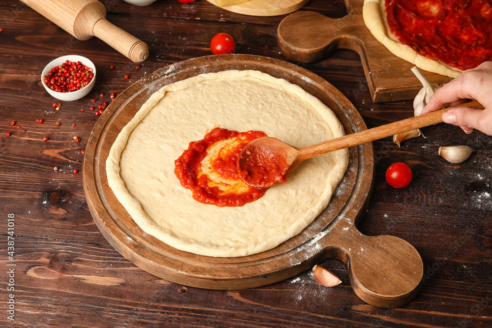 Woman preparing tasty pizza on wooden table