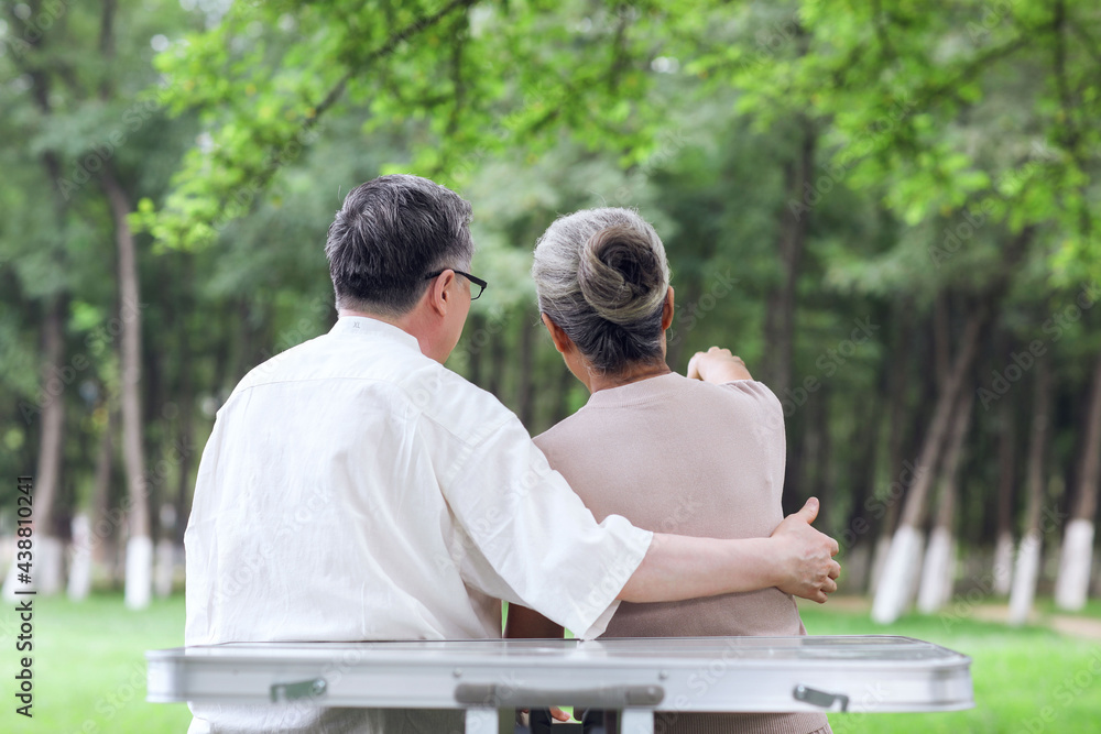 Happy old couple sitting on chairs in outdoor park