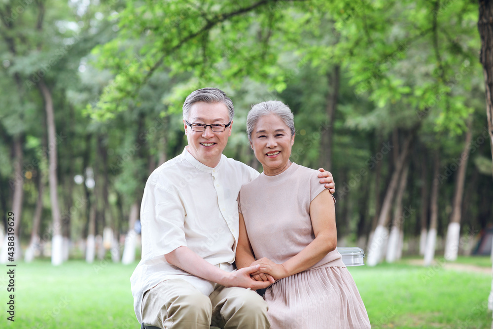 Happy old couple sitting on chairs in outdoor park