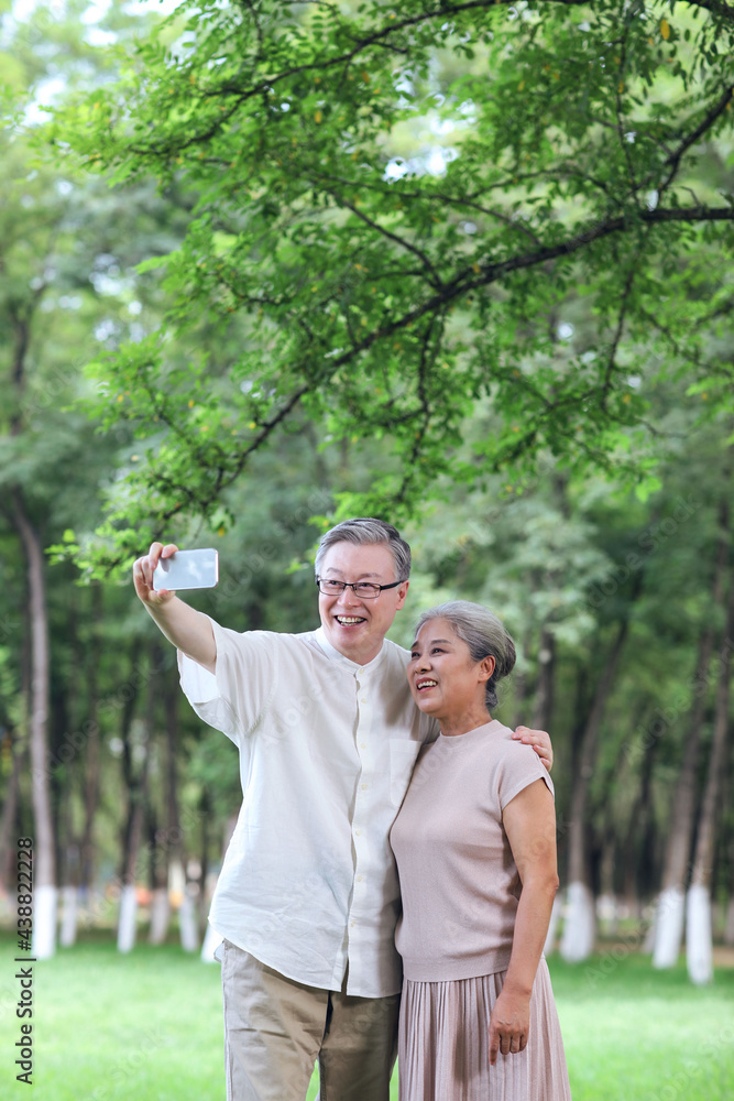 幸福的老夫妻在公园用手机自拍