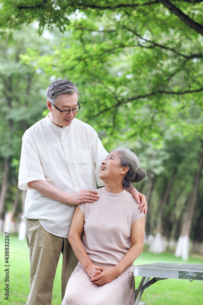 Happy old couple sitting on chairs in outdoor park