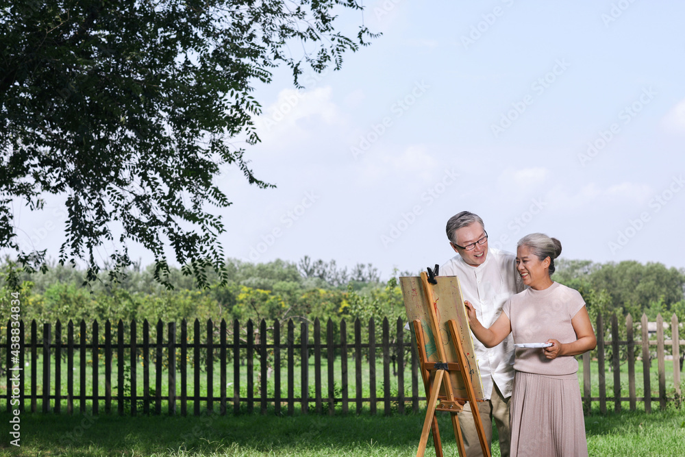 Happy old couple painting in the park