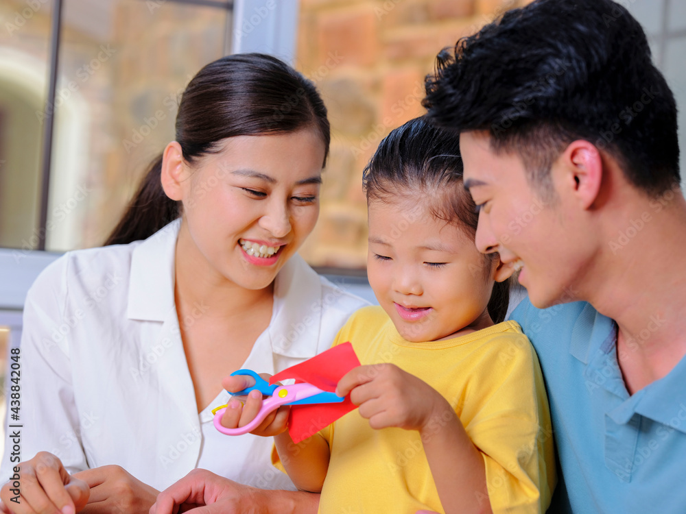 A happy family of three doing paper cutting in the living room