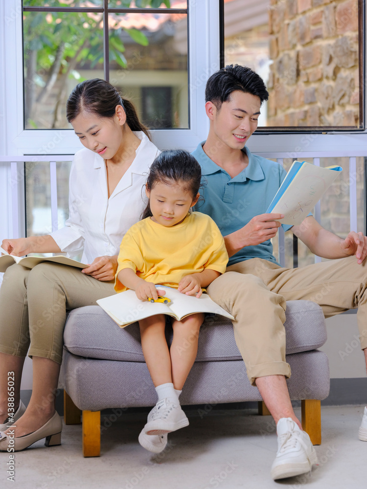 A happy family of three reading on the sofa