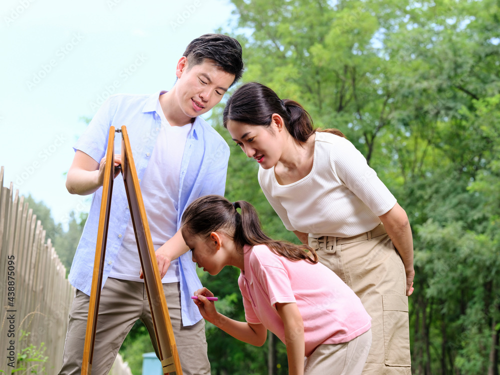 Happy family of three painting in the park