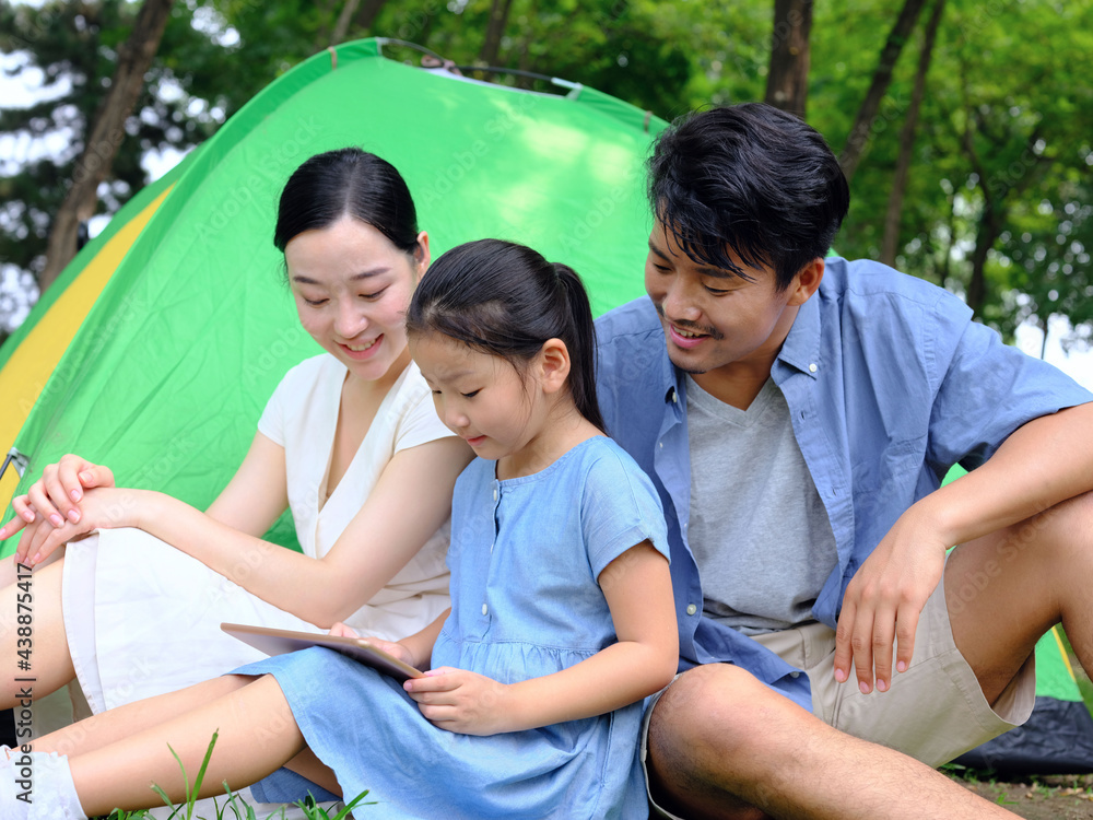 Happy family of three uses tablet computer outdoors