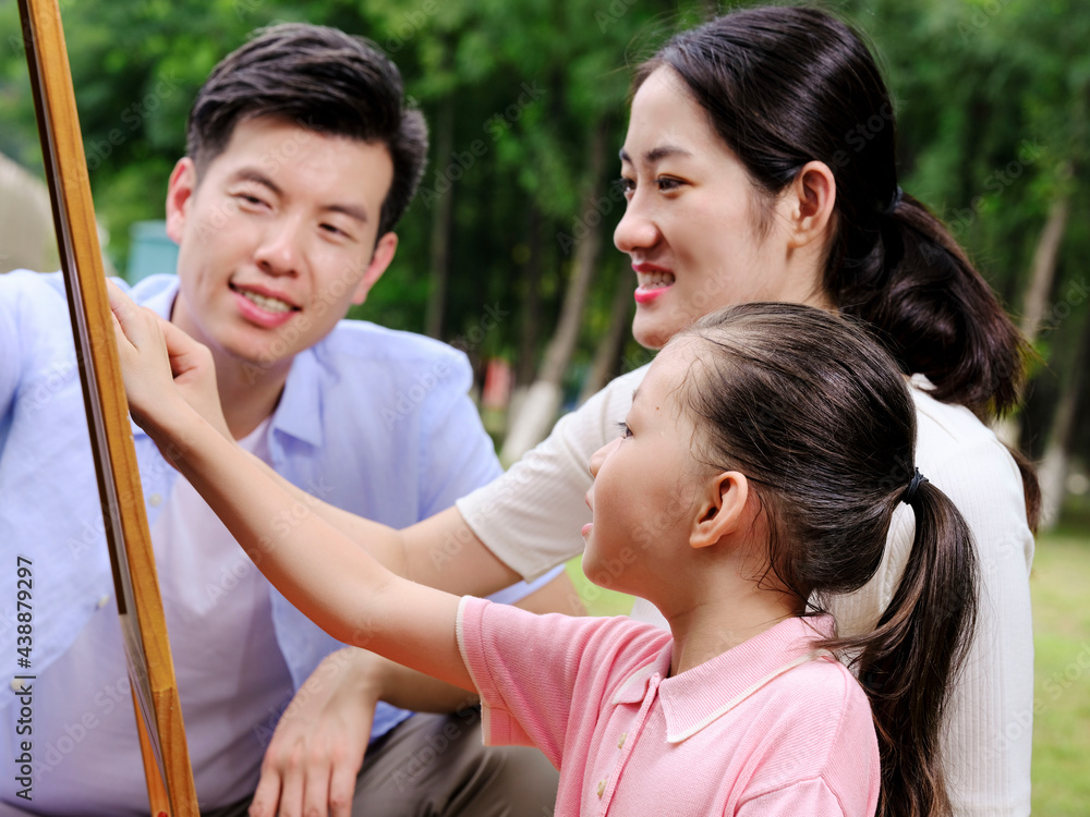 Happy family of three painting in the park