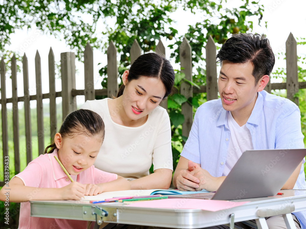 Young parents help their children with their homework outdoors