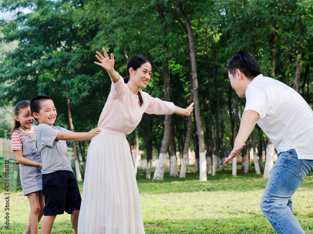 Happy family of four playing in the park