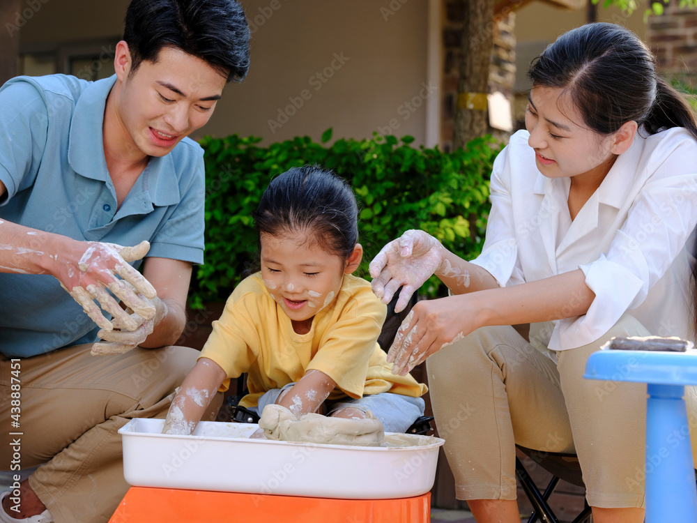 Happy family of three doing pottery together outdoors