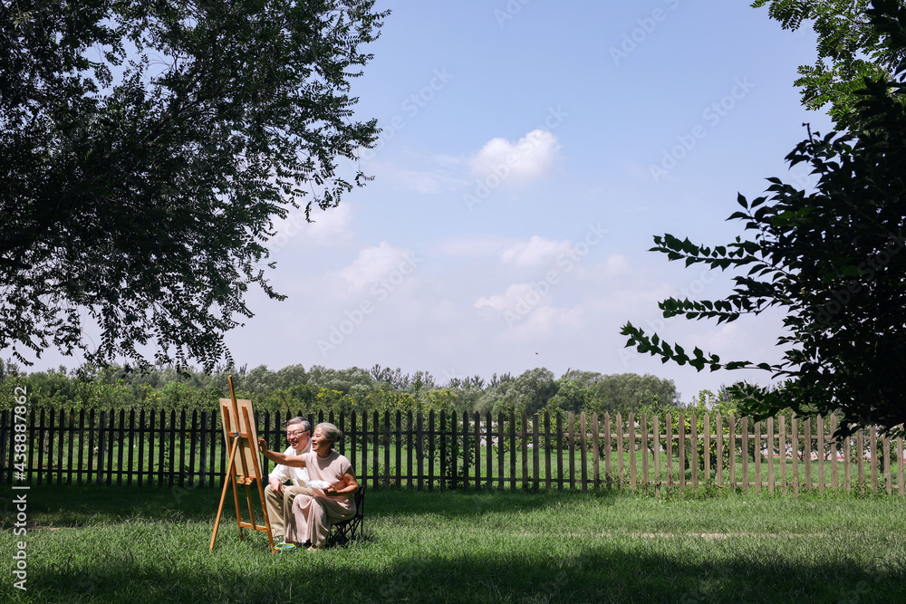 Happy old couple painting in the park