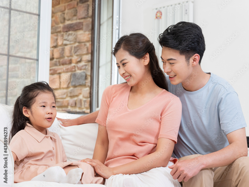 A happy family of three is sitting on the sofa in the living room