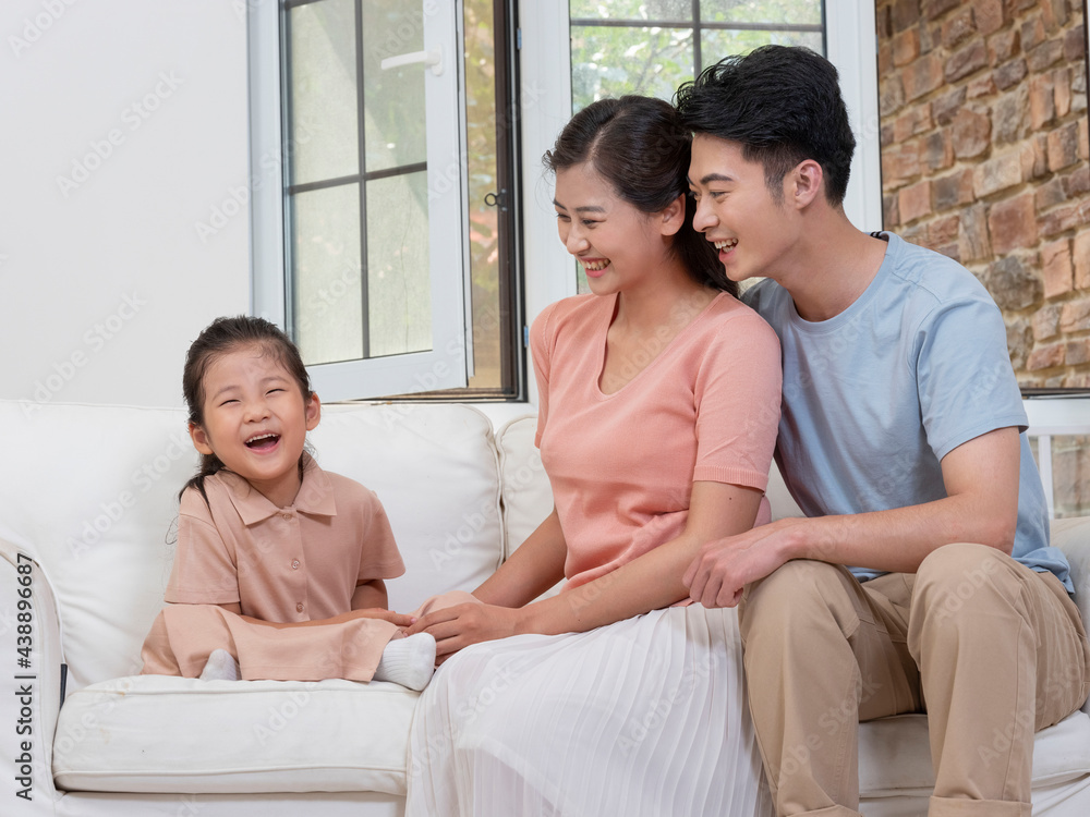 A happy family of three is sitting on the sofa in the living room