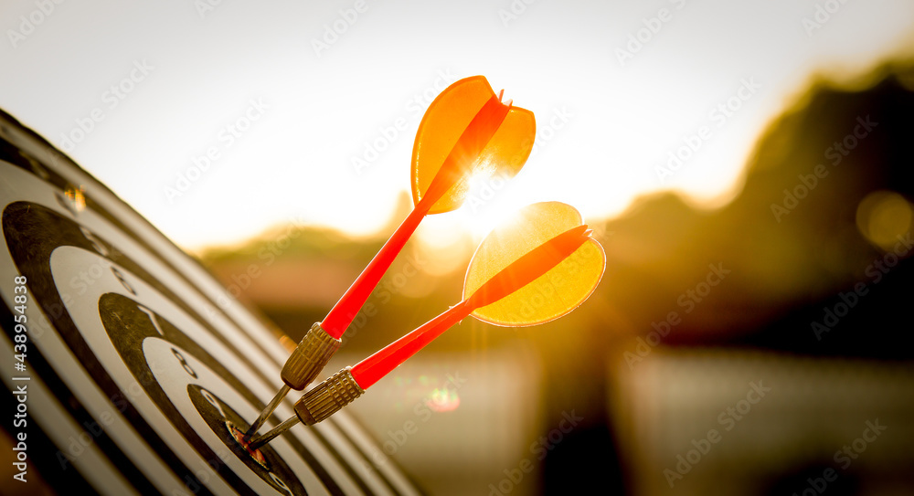 Close up shot red darts arrows in the target  of dartboard center on dark blue sky background. Busin