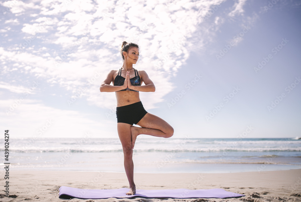 Woman at beach practicing yoga tree position