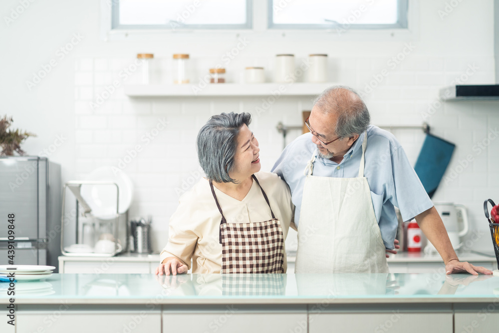 Asian Senior older Couple smile, look at each other in kitchen at home	