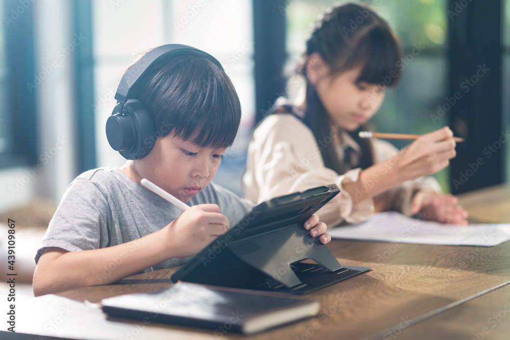 亚洲在家上学的男孩和女孩在家使用平板电脑在线学习。