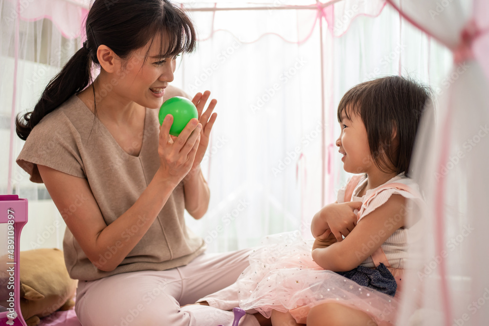 妈妈在家里的帐篷里教小女孩球玩具的颜色