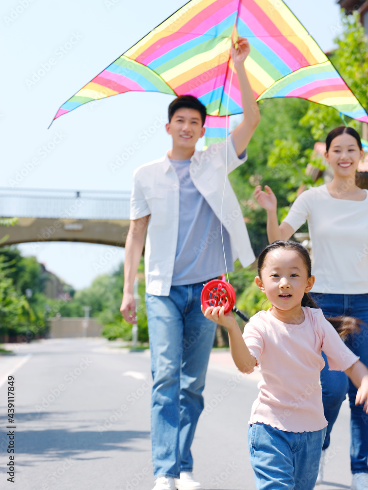 Happy family of three flying kites outdoors