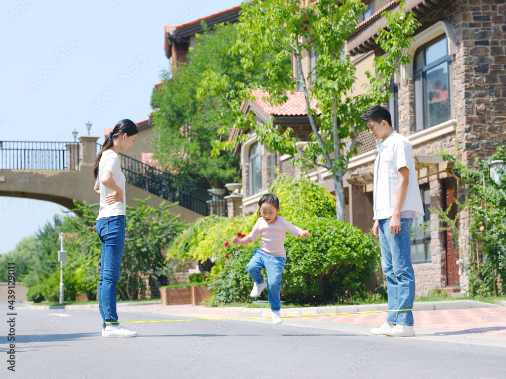 A happy family of three skipping rope outdoors