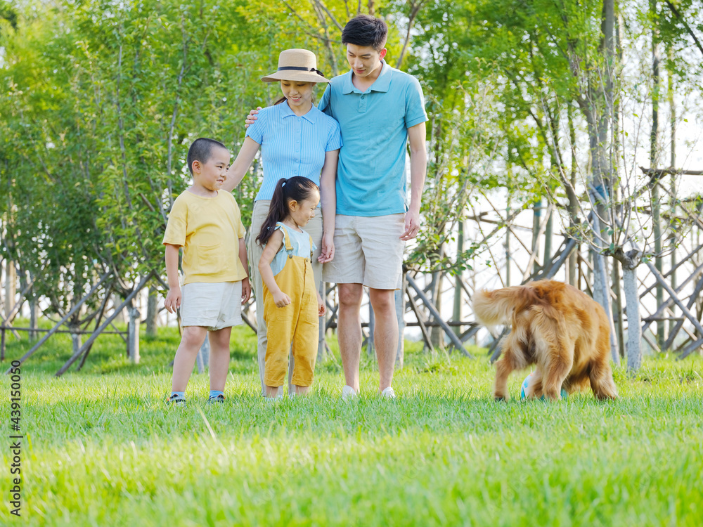 Happy family of four and pet dog playing in the park