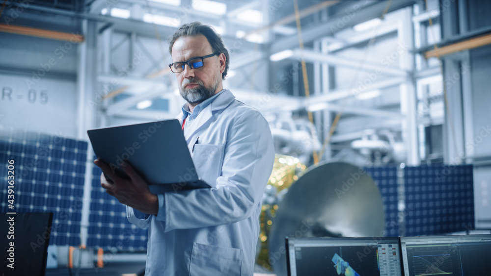 Male Engineer Confident and Focused Thinking, working on Laptop at Aerospace Satellite Manufacturing