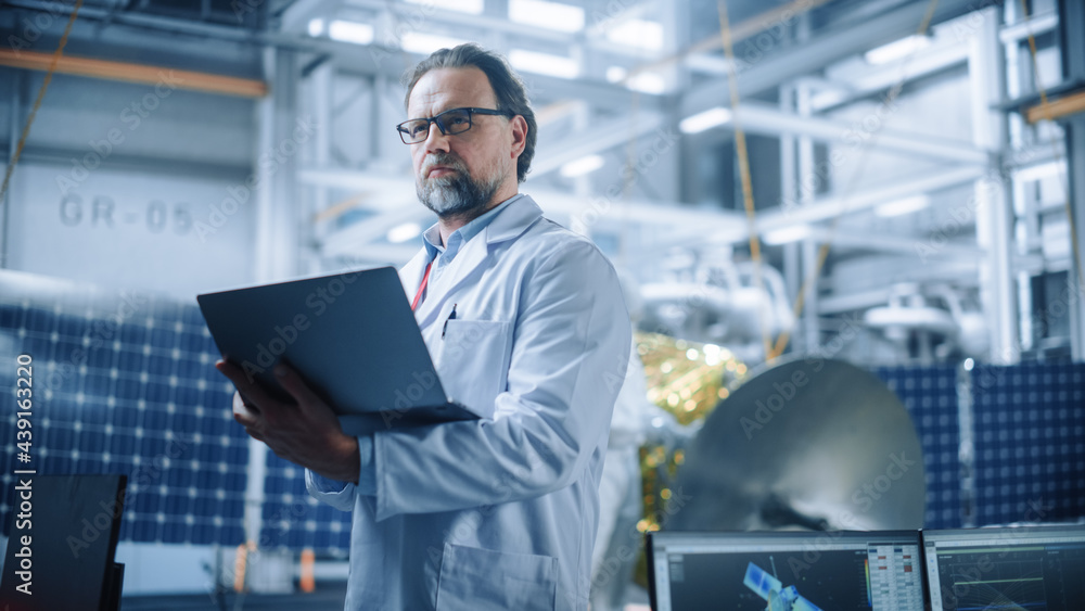 Male Engineer Confident and Focused Thinking, working on Laptop at Aerospace Satellite Manufacturing