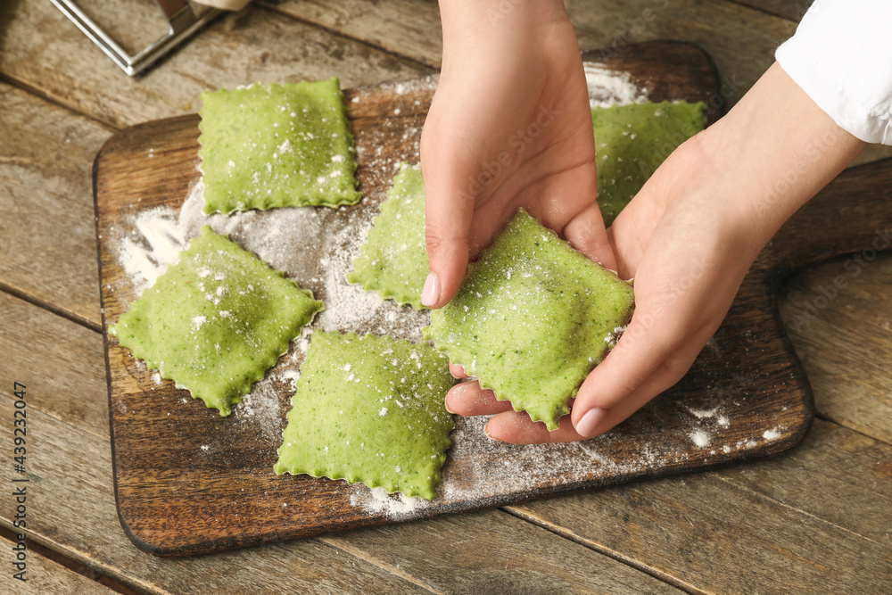 Female chef making delicious ravioli at table, closeup