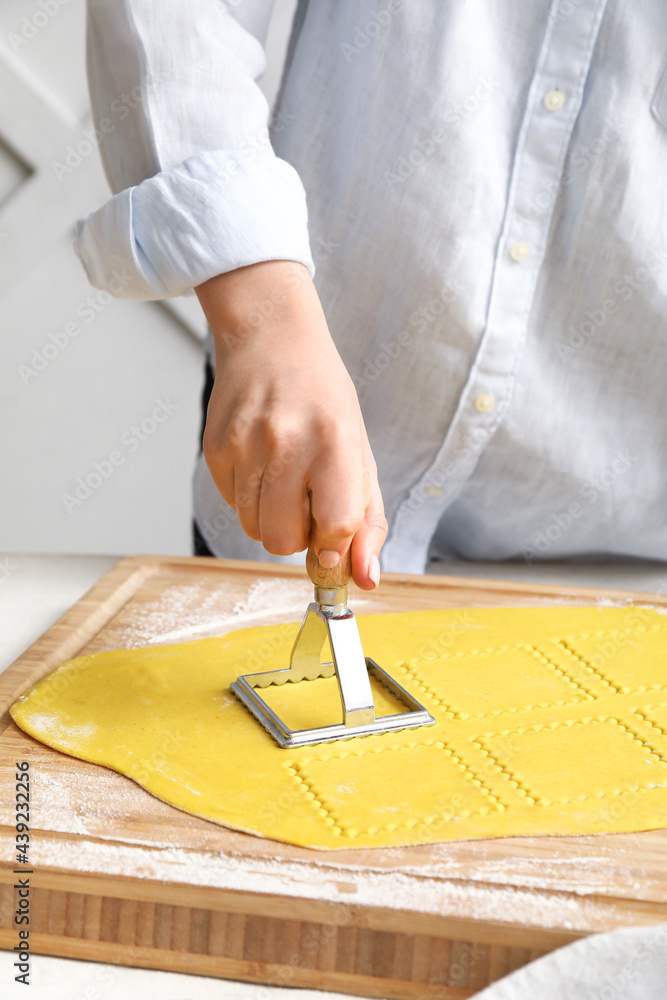 Female chef making delicious ravioli at table, closeup