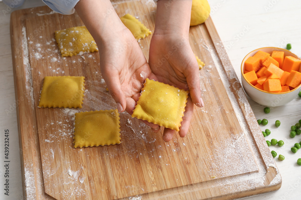 Female chef making delicious ravioli at table, closeup