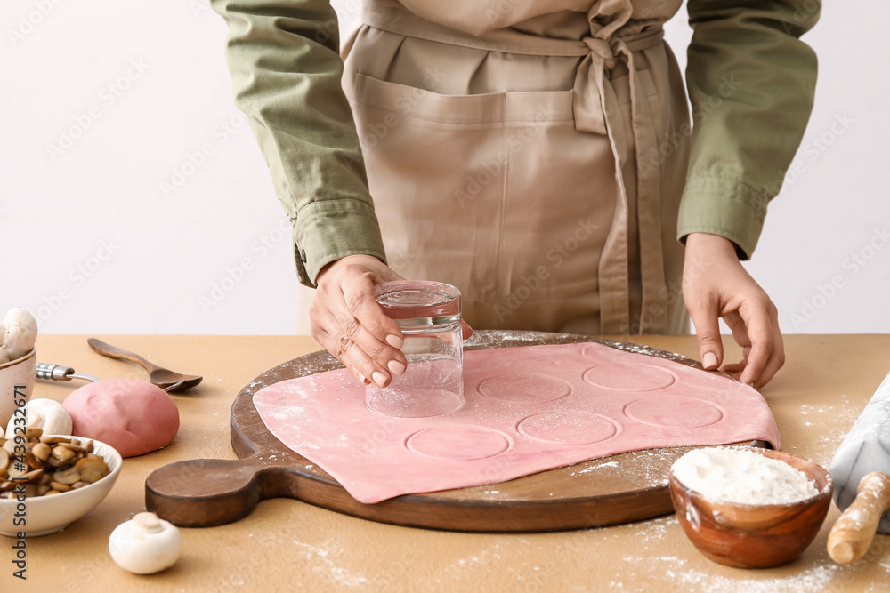 Female chef making delicious ravioli at table, closeup