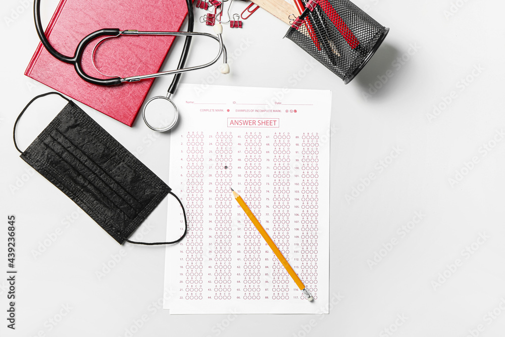 Answer sheet, stethoscope, mask and stationery on white background