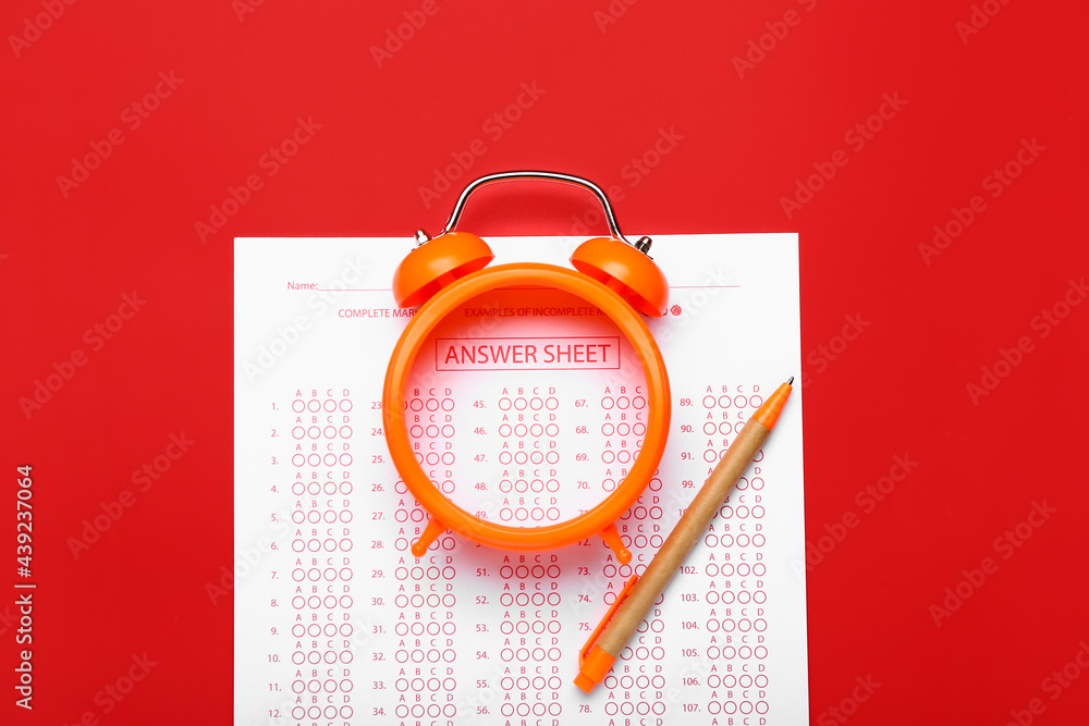 Answer sheet, pen and alarm clock on color background