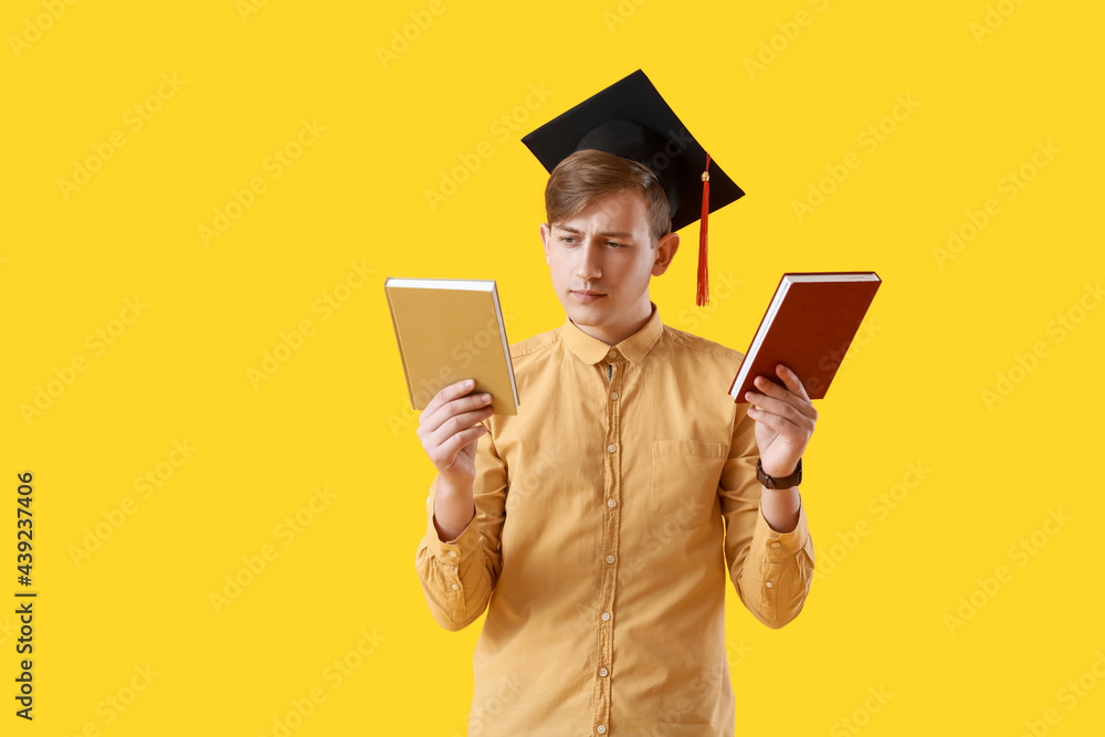 Male graduating student with books on color background