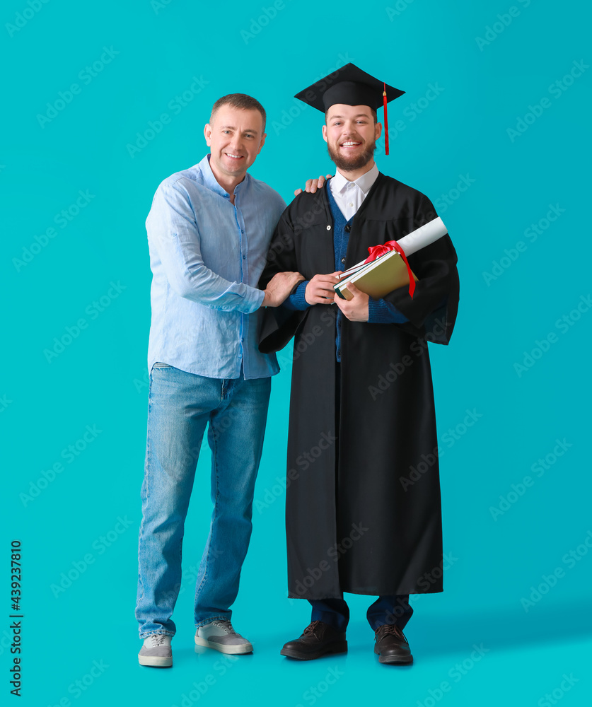 Happy male graduation student with his father on color background