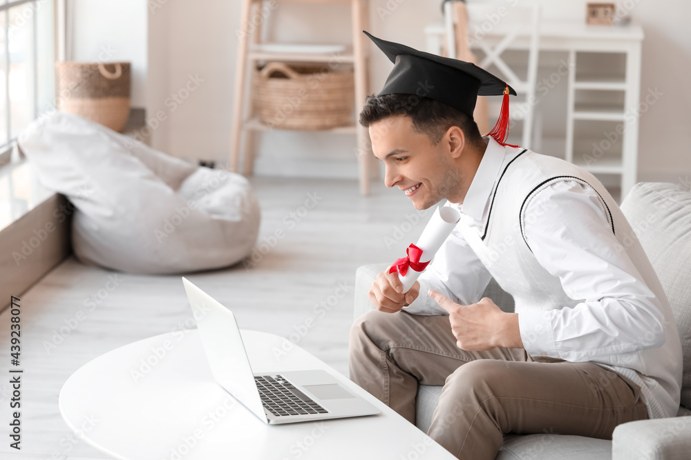 Happy male student on his graduation day at home. Concept of online education