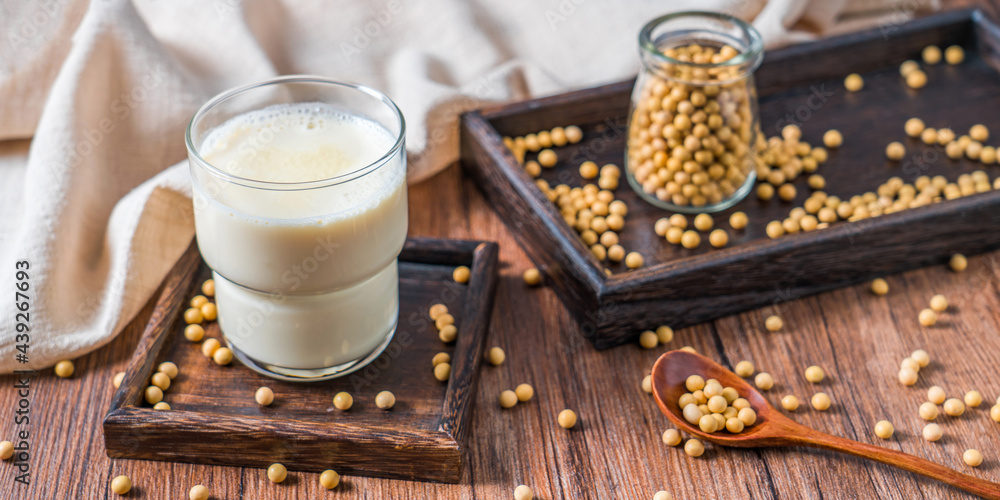 Many soybeans and a cup of soy milk on the bamboo mat